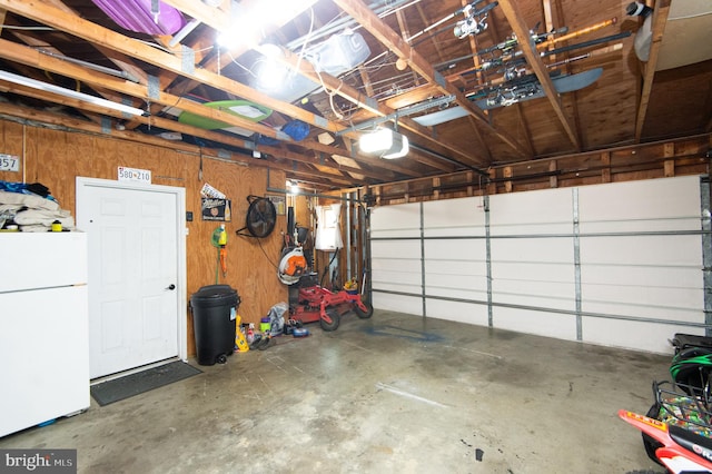 garage with white refrigerator, wooden walls, and a garage door opener