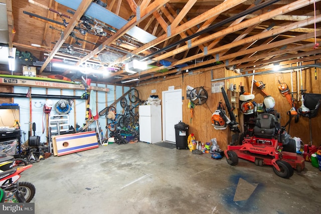 garage with white refrigerator, a garage door opener, and wood walls