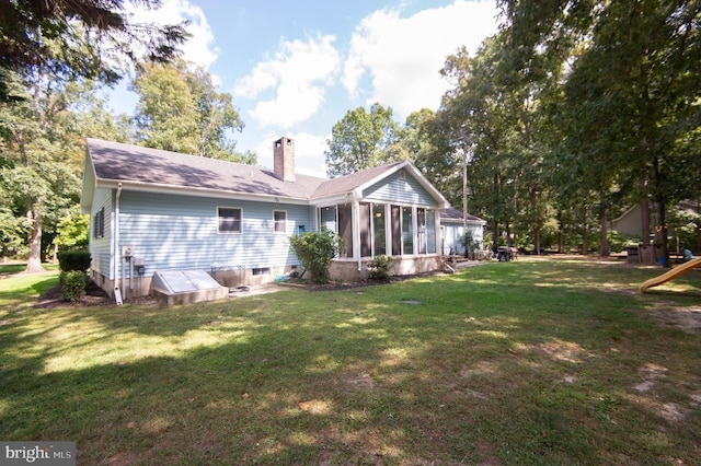 back of house featuring a lawn and a sunroom