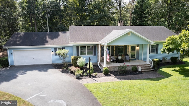 ranch-style home featuring a garage, covered porch, and a front yard