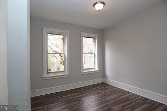 empty room featuring dark wood finished floors and baseboards