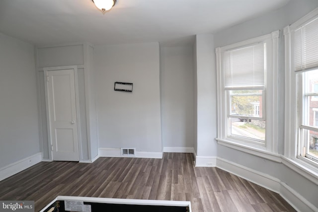 empty room featuring baseboards, visible vents, and dark wood-style flooring