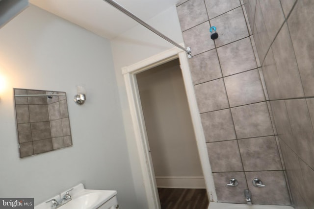 bathroom featuring wood-type flooring, sink, and tiled shower