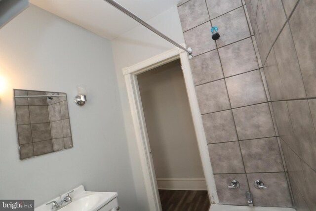 bathroom featuring washtub / shower combination, toilet, baseboards, and wood finished floors