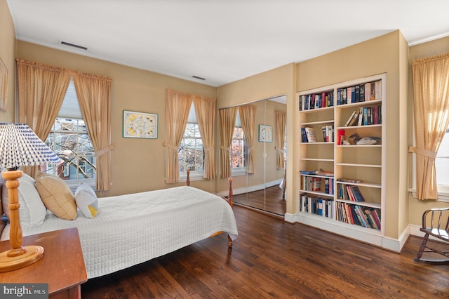 bedroom with dark hardwood / wood-style flooring, a closet, and multiple windows