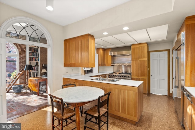 kitchen featuring kitchen peninsula, stainless steel range, sink, and ventilation hood