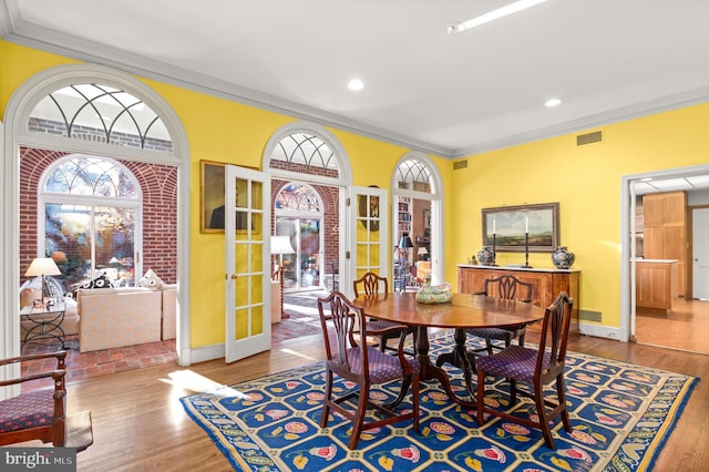 dining space featuring french doors, hardwood / wood-style flooring, and crown molding