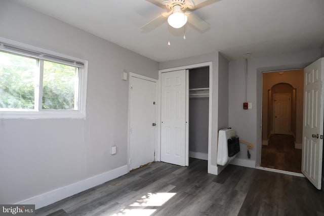 unfurnished bedroom featuring heating unit, dark hardwood / wood-style floors, ceiling fan, and a closet