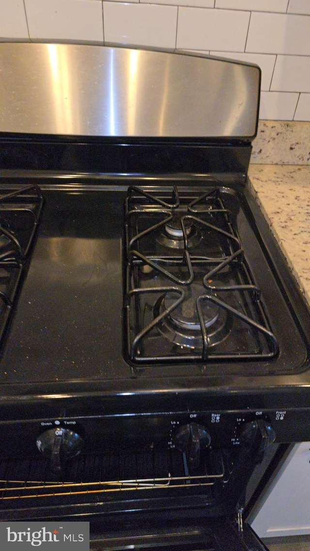 interior details with light stone countertops, stainless steel gas range, and tasteful backsplash