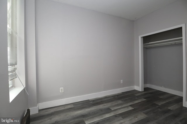 unfurnished bedroom with a closet and dark hardwood / wood-style flooring