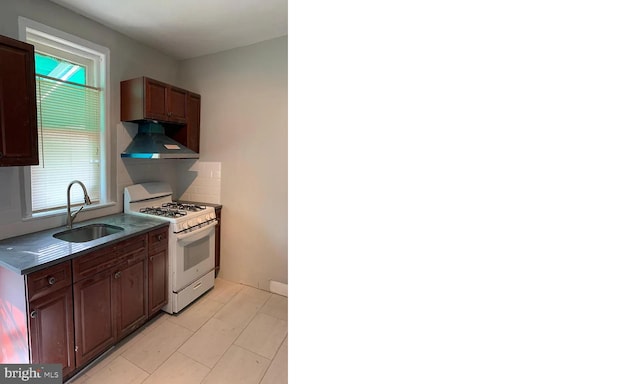 kitchen featuring white range with gas cooktop, tasteful backsplash, sink, and range hood