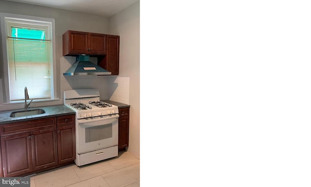 kitchen featuring light tile patterned floors, white range with gas stovetop, sink, and wall chimney range hood