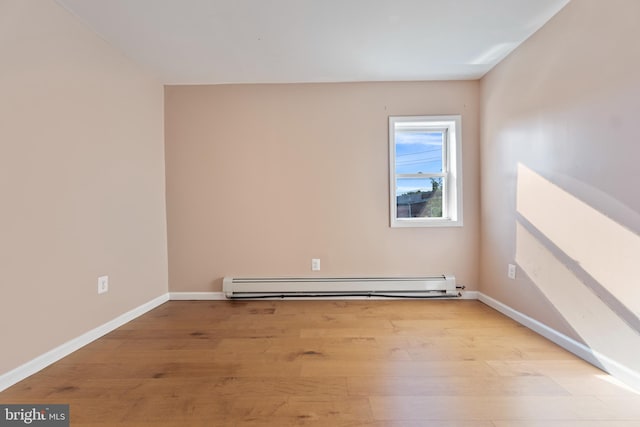 empty room featuring a baseboard radiator and light hardwood / wood-style floors