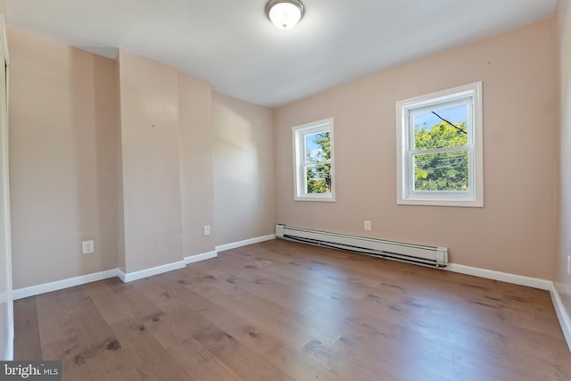 spare room with baseboard heating and light hardwood / wood-style floors