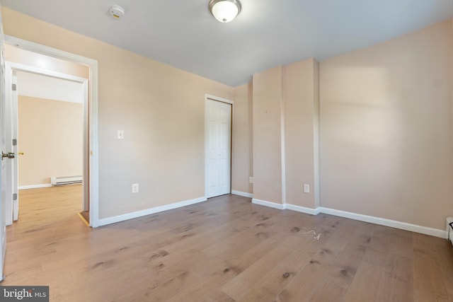 unfurnished bedroom featuring a baseboard radiator, a closet, and light wood-type flooring