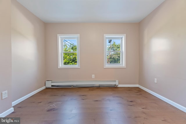 unfurnished room featuring a baseboard radiator, a wealth of natural light, and light hardwood / wood-style flooring