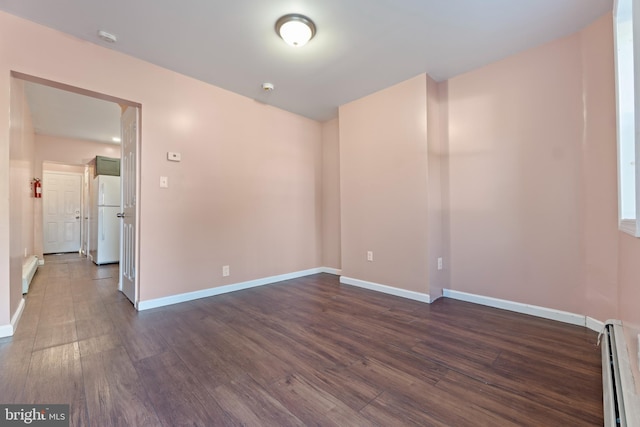 unfurnished room featuring a baseboard heating unit and dark hardwood / wood-style flooring