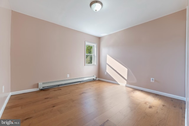 spare room with baseboard heating and light hardwood / wood-style floors