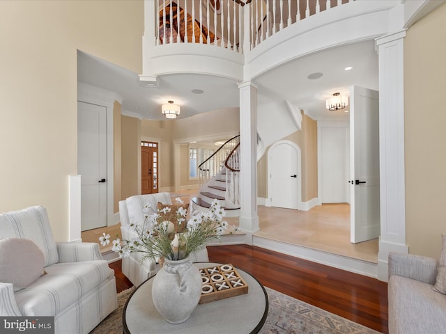 interior space featuring a high ceiling, hardwood / wood-style floors, and decorative columns