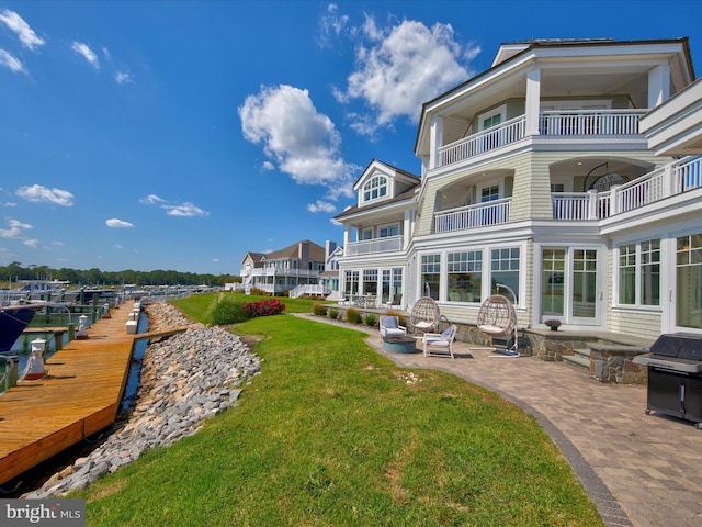 back of property featuring a balcony, an outdoor fire pit, a yard, and a patio