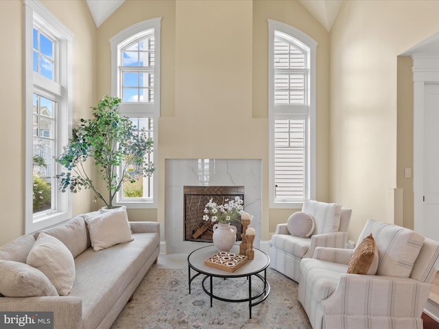 living room featuring a premium fireplace and high vaulted ceiling