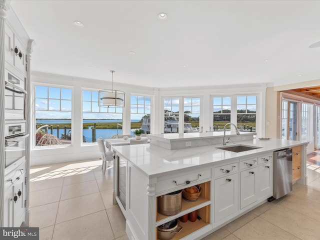 kitchen with a kitchen island with sink, decorative light fixtures, dishwasher, sink, and white cabinets