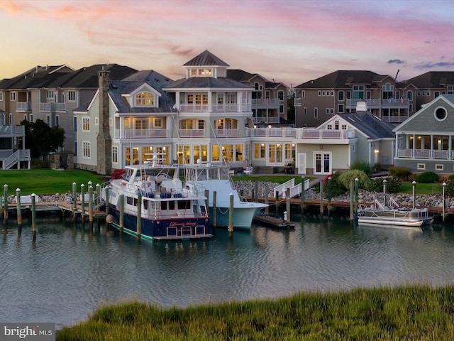 back house at dusk featuring a water view and a balcony