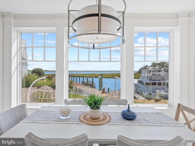 dining space with a water view, ornamental molding, and a healthy amount of sunlight