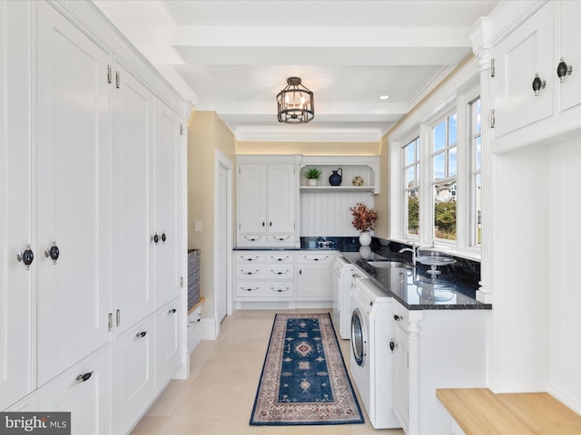 kitchen featuring dark stone countertops, independent washer and dryer, white cabinetry, sink, and ornamental molding