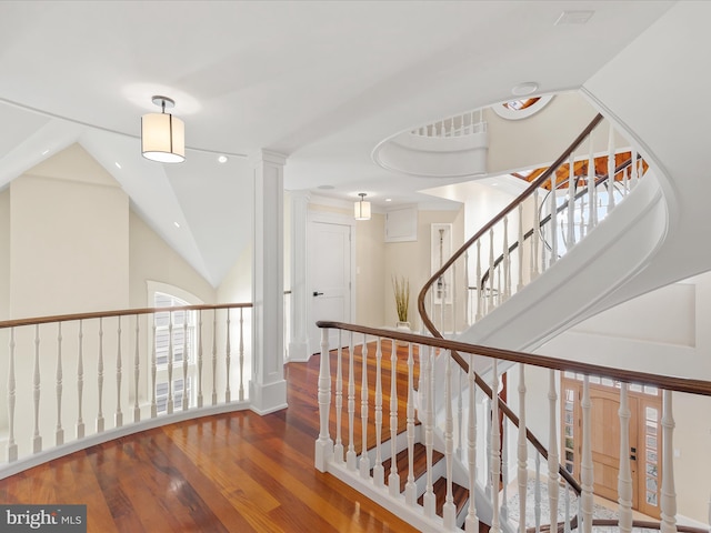 stairs with vaulted ceiling, wood-type flooring, and a healthy amount of sunlight