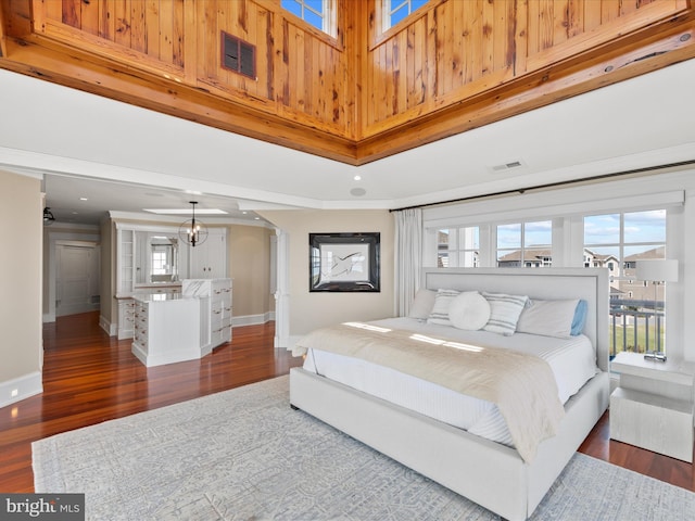 bedroom with a towering ceiling, dark wood-type flooring, and an inviting chandelier