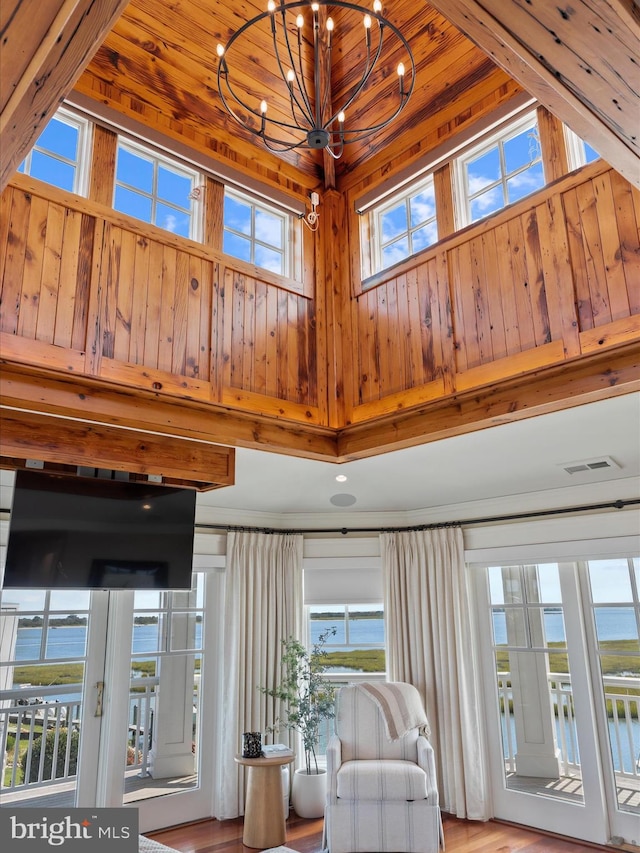 interior space featuring plenty of natural light, an inviting chandelier, a towering ceiling, and a water view