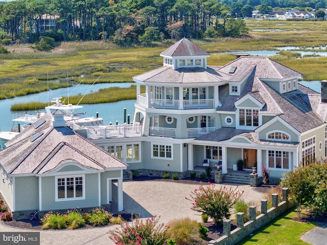 rear view of house featuring a balcony and a water view