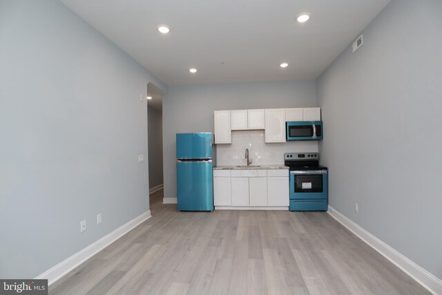 kitchen with stainless steel appliances, sink, light wood-type flooring, and decorative backsplash