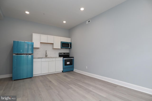 kitchen with light wood-type flooring, appliances with stainless steel finishes, sink, and white cabinets