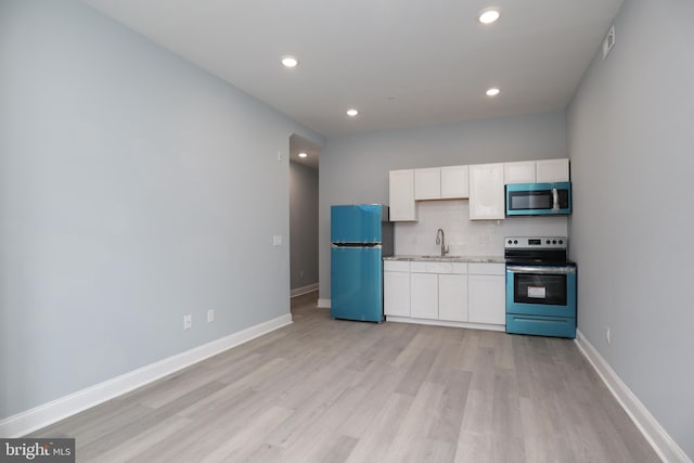 kitchen featuring appliances with stainless steel finishes, tasteful backsplash, light hardwood / wood-style floors, and white cabinetry