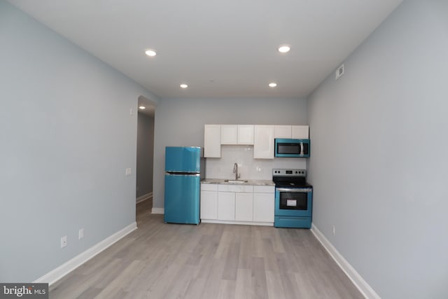 kitchen with light wood-type flooring, appliances with stainless steel finishes, white cabinetry, and sink