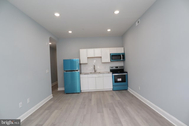 kitchen with backsplash, stainless steel appliances, light wood-type flooring, and white cabinetry