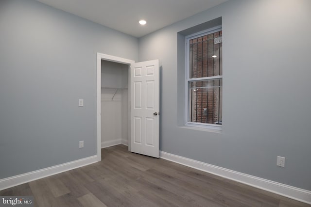 unfurnished bedroom with a closet and dark hardwood / wood-style floors