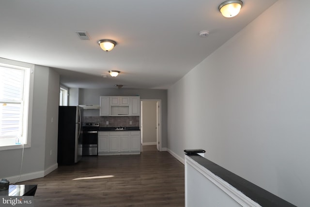 kitchen featuring dark wood-type flooring, a wealth of natural light, stainless steel appliances, and white cabinets