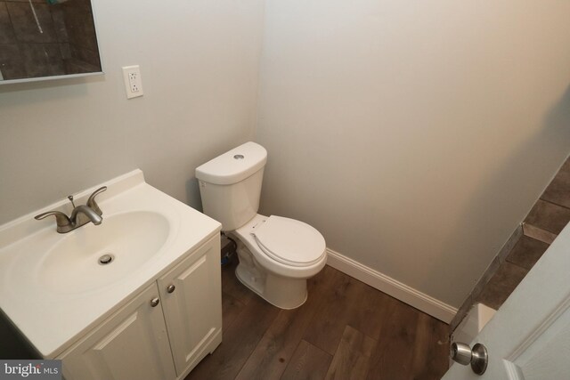 bathroom with toilet, hardwood / wood-style flooring, and vanity