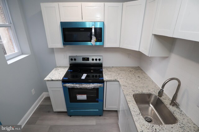 kitchen featuring stainless steel appliances, sink, light wood-type flooring, and white cabinetry