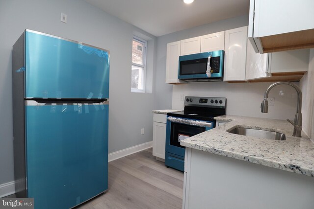 kitchen featuring white cabinetry, light hardwood / wood-style flooring, light stone counters, sink, and appliances with stainless steel finishes