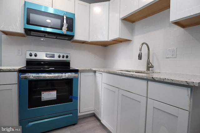 kitchen with tasteful backsplash, light stone counters, sink, appliances with stainless steel finishes, and white cabinets