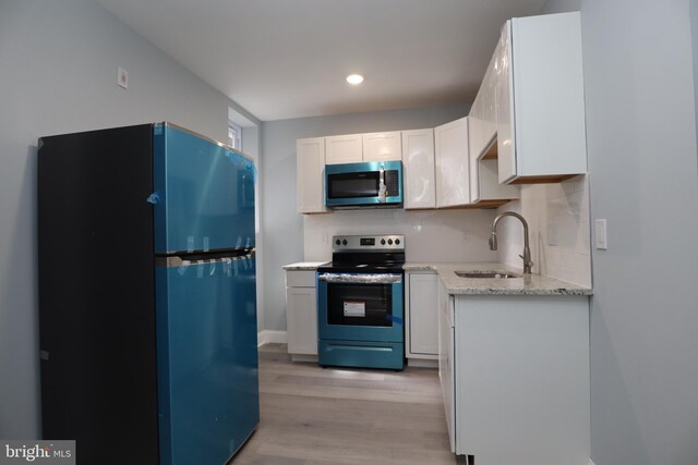 kitchen with light wood-type flooring, white cabinets, stainless steel appliances, and sink