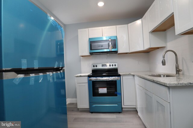 kitchen featuring white cabinetry, light hardwood / wood-style flooring, light stone counters, sink, and appliances with stainless steel finishes