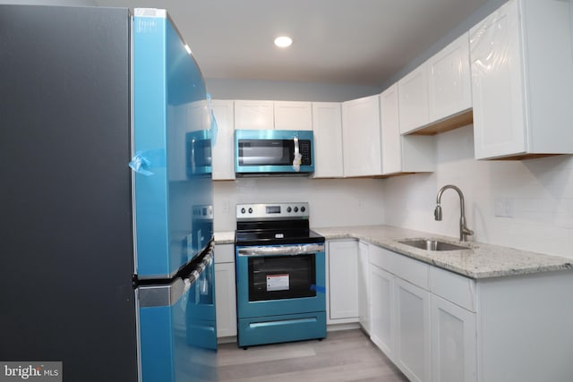 kitchen featuring light hardwood / wood-style flooring, stainless steel appliances, sink, white cabinetry, and light stone counters