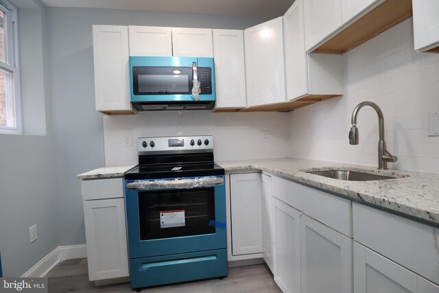 kitchen featuring light wood-type flooring, appliances with stainless steel finishes, white cabinetry, and sink