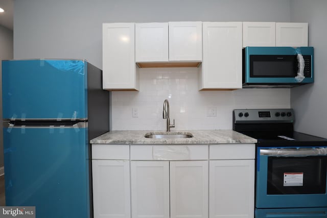 kitchen featuring white cabinetry, stainless steel appliances, light stone counters, sink, and decorative backsplash