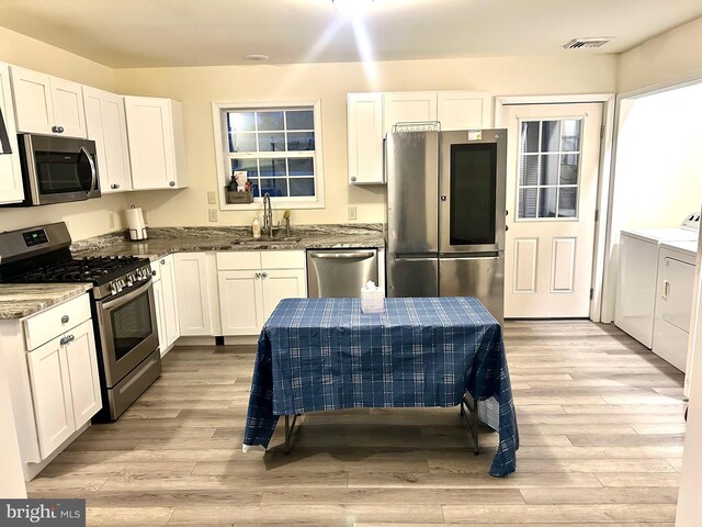 5601 Briarwood Dr, Millville, NJ 08332 - kitchen with stainless steel appliances, washer and clothes dryer, a sink, dark stone countertops, and white cabinetry
